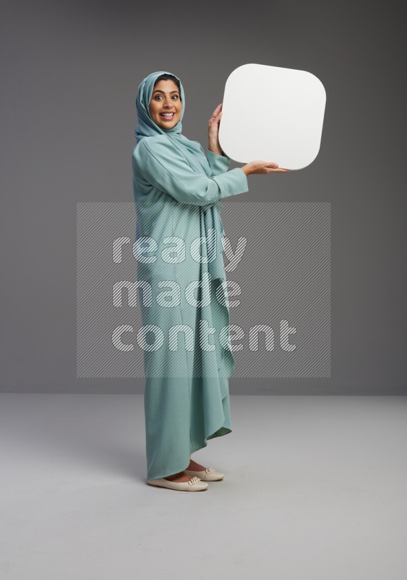 Saudi Woman wearing Abaya standing holding social media sign on Gray background