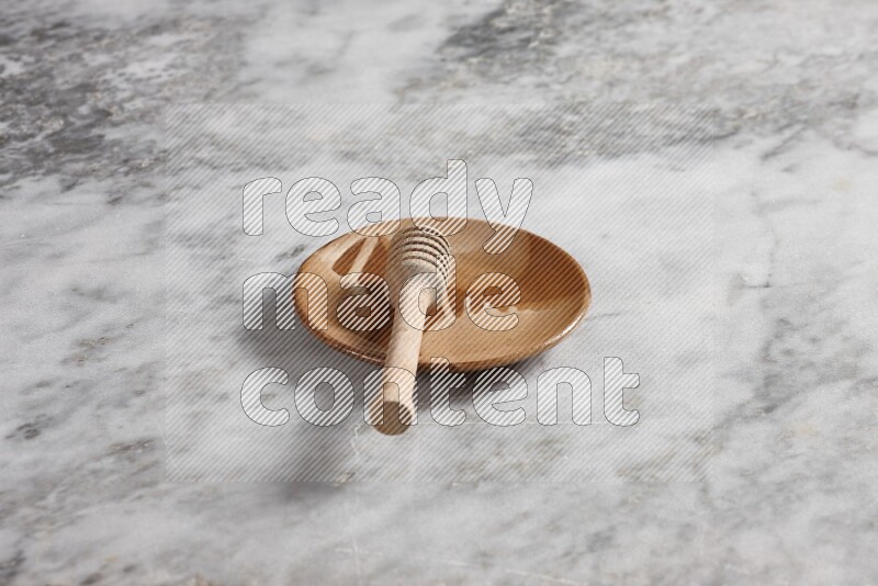 Multicolored pottery plate with wooden honey dipper in it on grey marble background