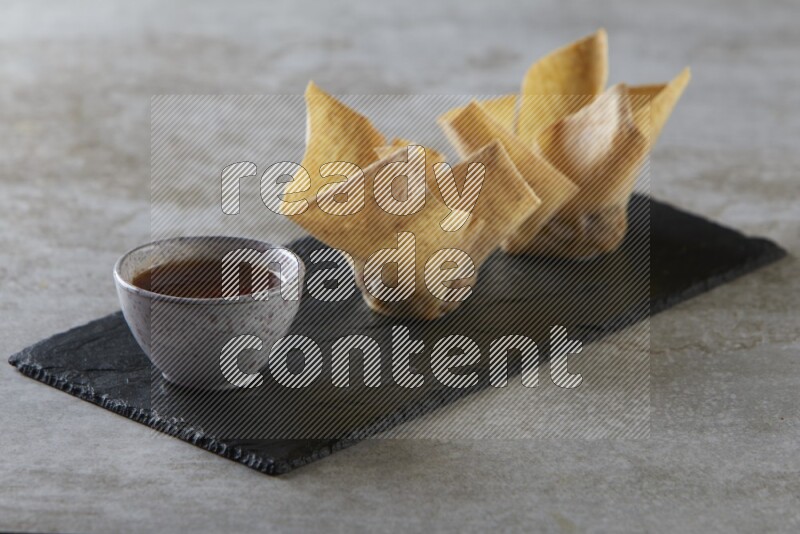 wonton cups with soy sauce ramkin on rectangle slate on grey textured counter top