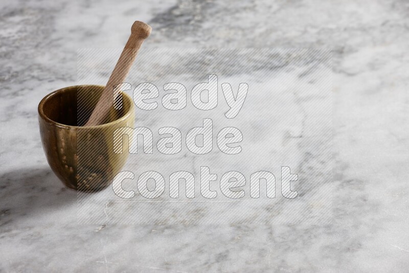 Multicolored pottery cup with wooden honey dipper in it on grey marble background