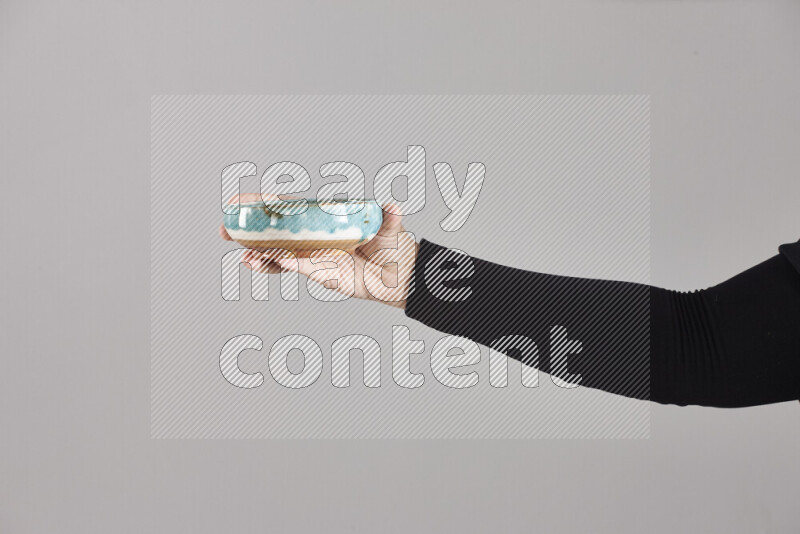 A woman in black abaya holding different pottery essentials in different positions