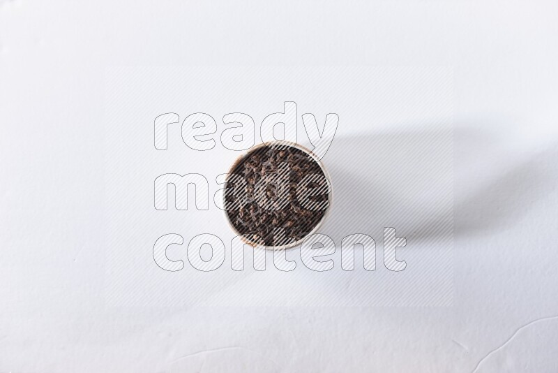 وعاء بيج من السيراميك ممتلئ بحبوب القرنفل علي خلفية بيضاء