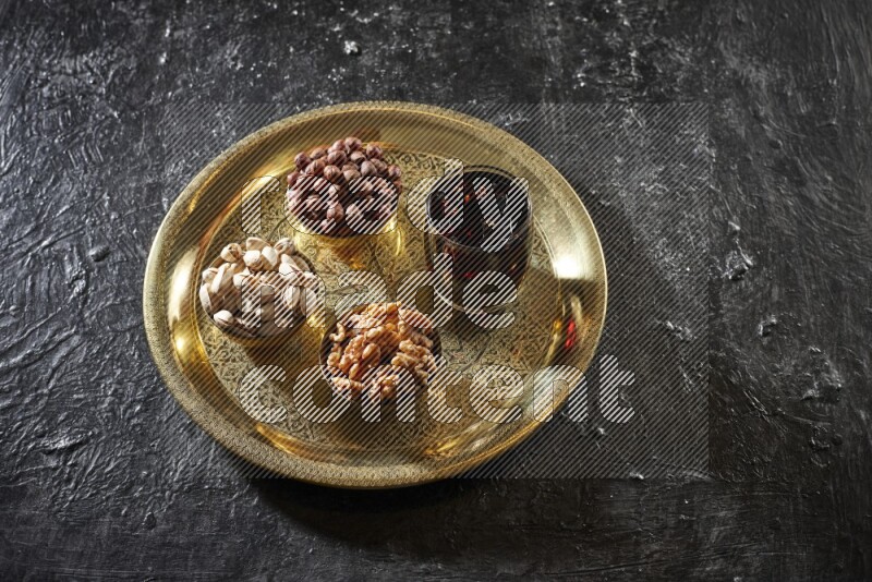 Nuts in metal bowls with tamarind on a tray in dark setup