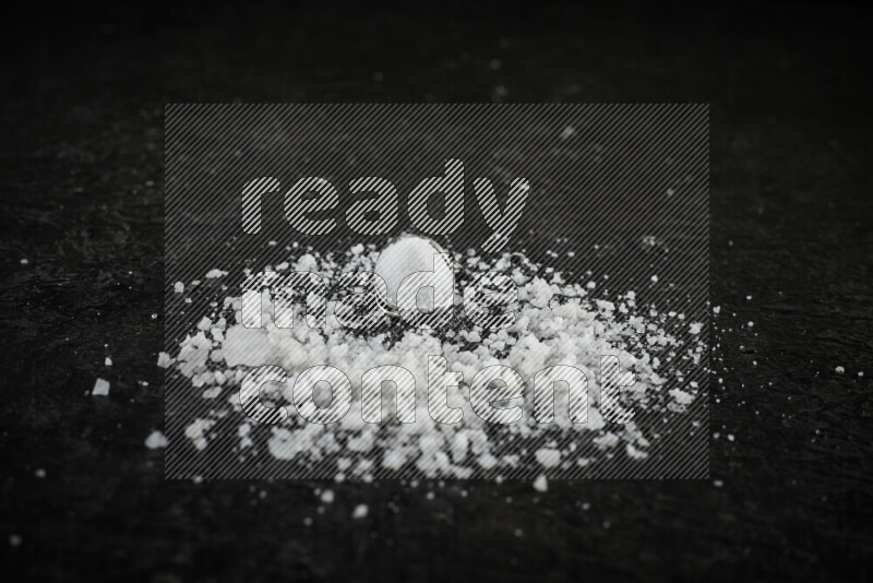 2 metal spoons filled with white salt on black background