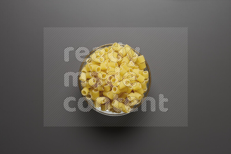 Big rings pasta in a glass bowl on grey background
