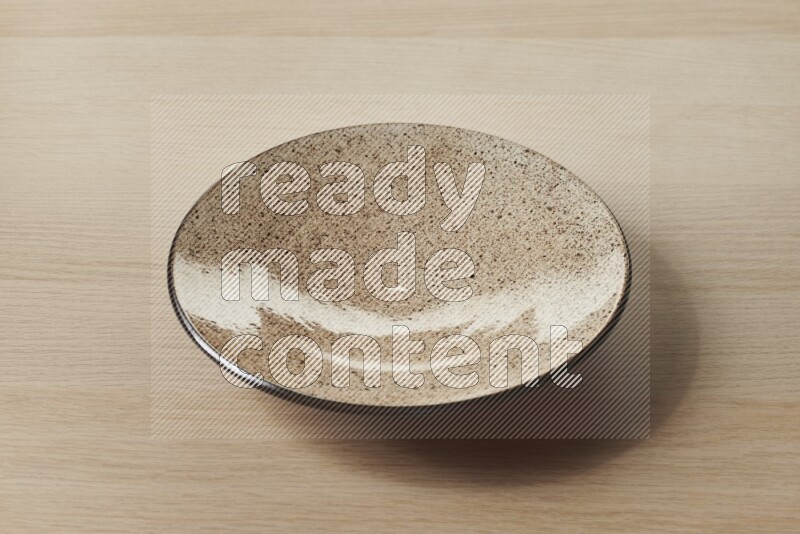 A beige pottery plate on light wooden background
