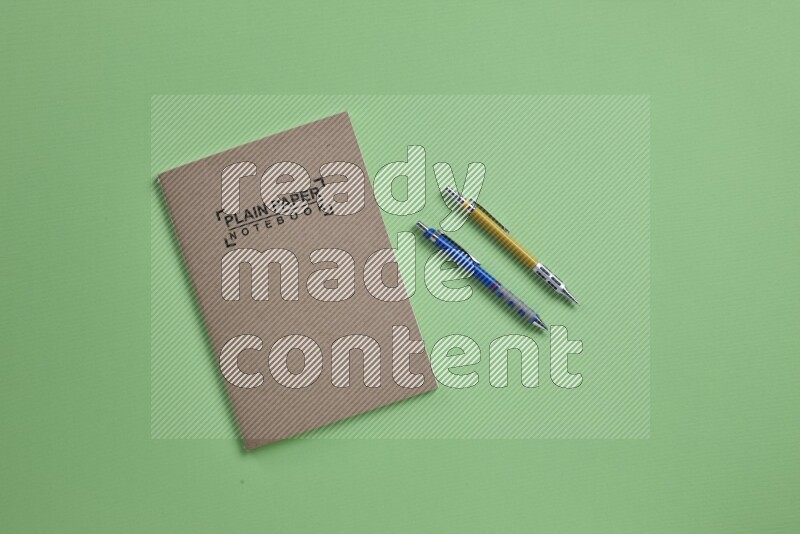 A notebook with different school supplies on green background