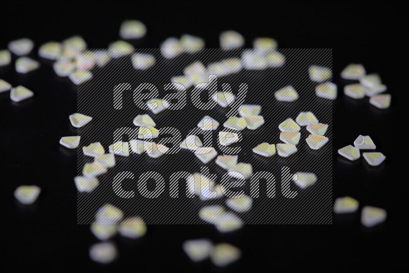 Colorful plastic shards for decoration scattered on a black background