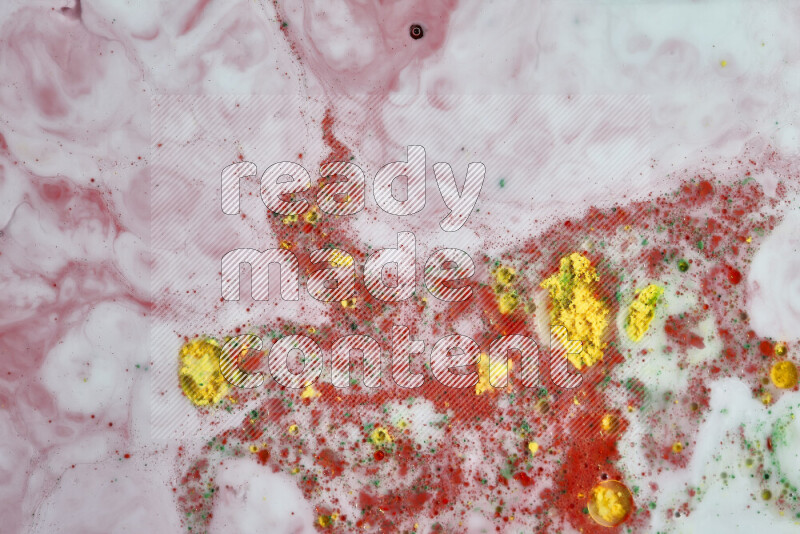 The image captures a splatter of yellow, red and green paint over a white backdrop