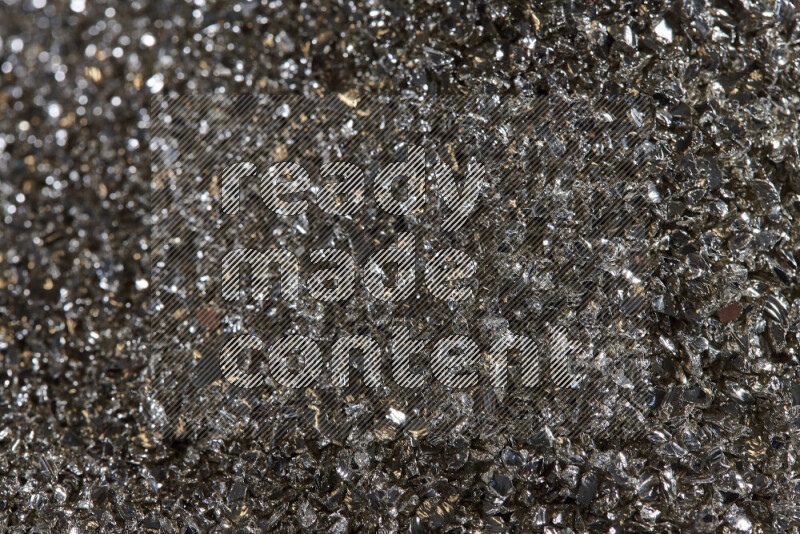 Silver shimmering fragments of glass scattered on a black background