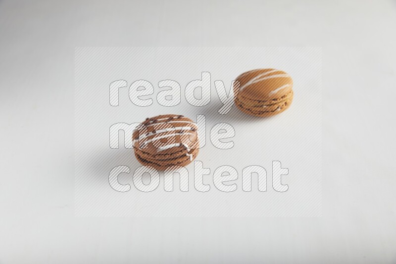 45º Shot of of two assorted Brown Irish Cream, and Brown white Chocolate Caramel macarons on white background