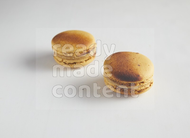 45º Shot of two Yellow Crème Brulée macarons on white background