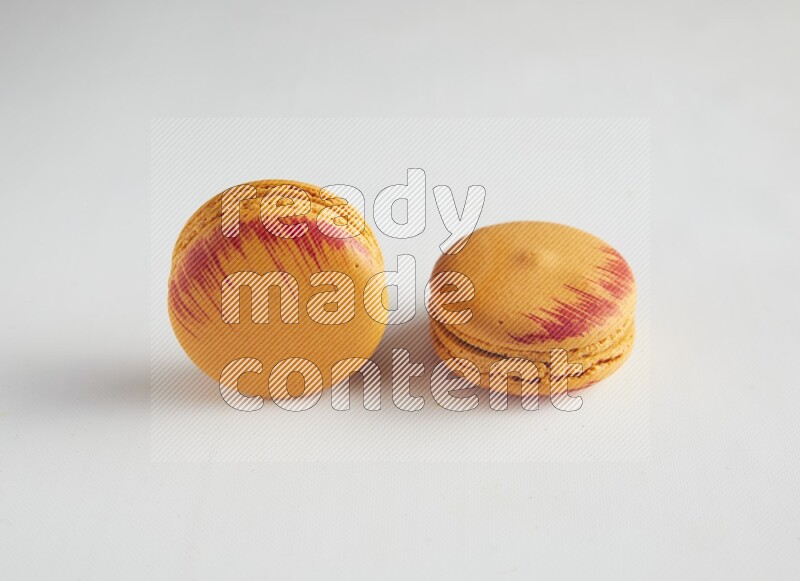 45º Shot of two orange Exotic macarons on white background