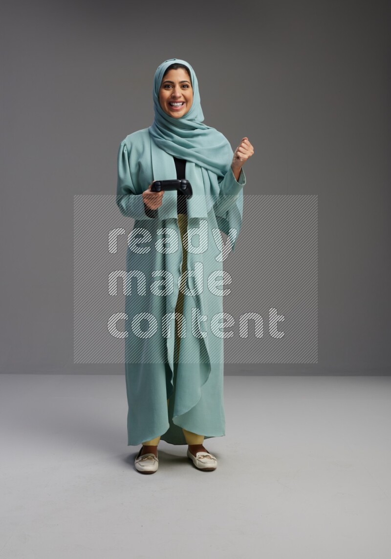 Saudi Woman wearing Abaya standing Playing Games on Gray background