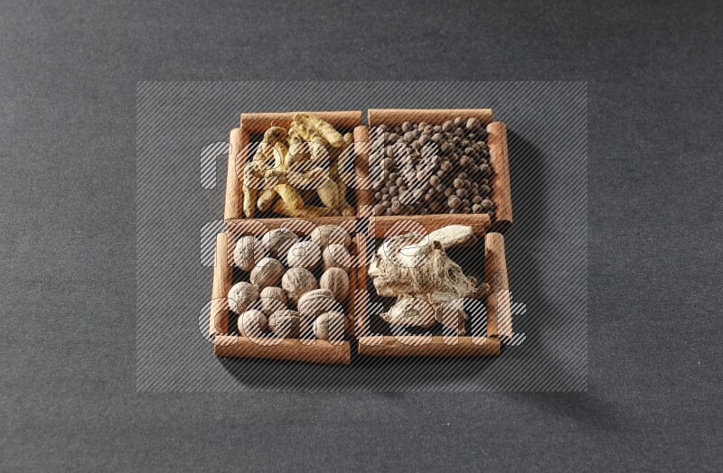 4 squares of cinnamon sticks full of turmeric fingers, allspice, dried ginger and nutmegs on black flooring