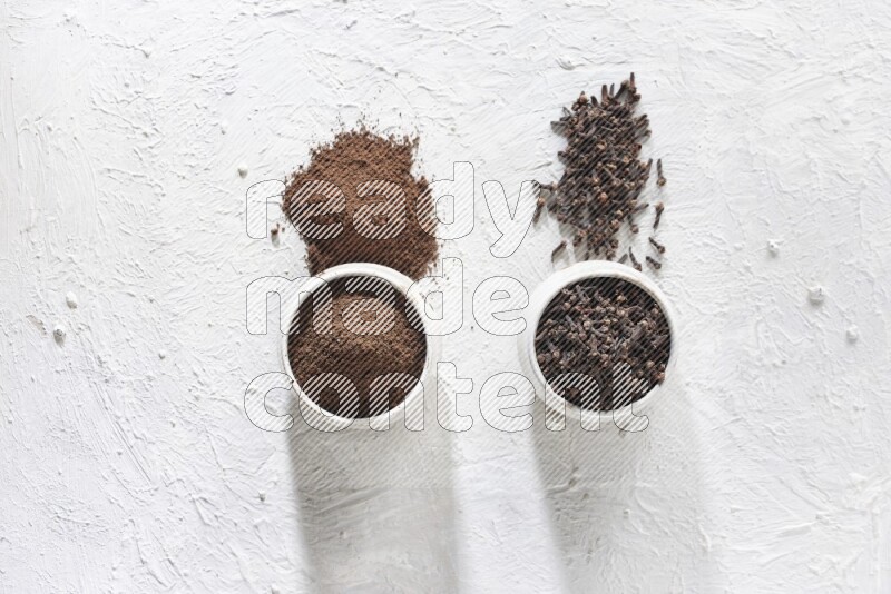 وعاءين من السيراميك بيج اللون، أحدهما مملوء بالقرنفل والآخر مملوء بالبودرة على أرضية بيضاء