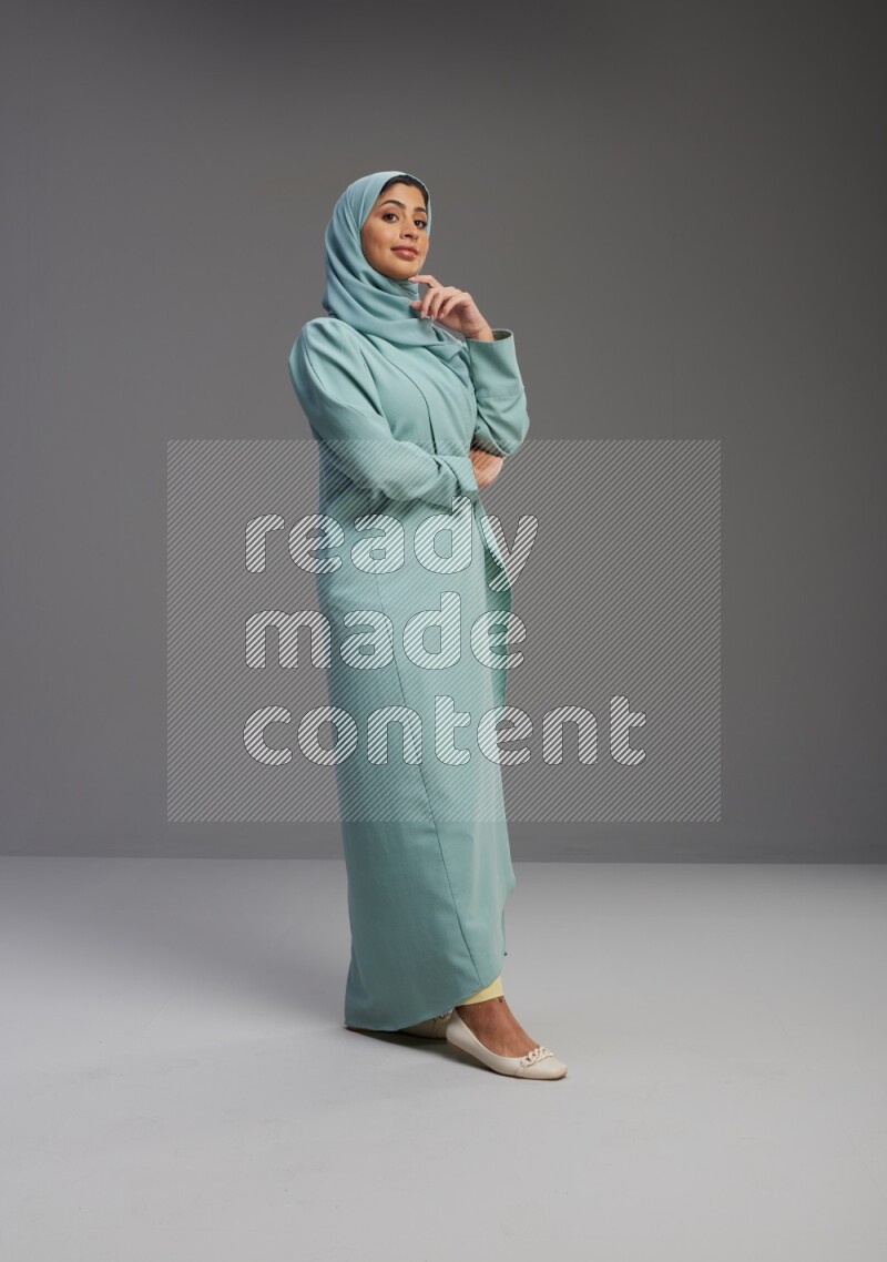 Saudi Woman wearing Abaya standing interacting with the camera on Gray background