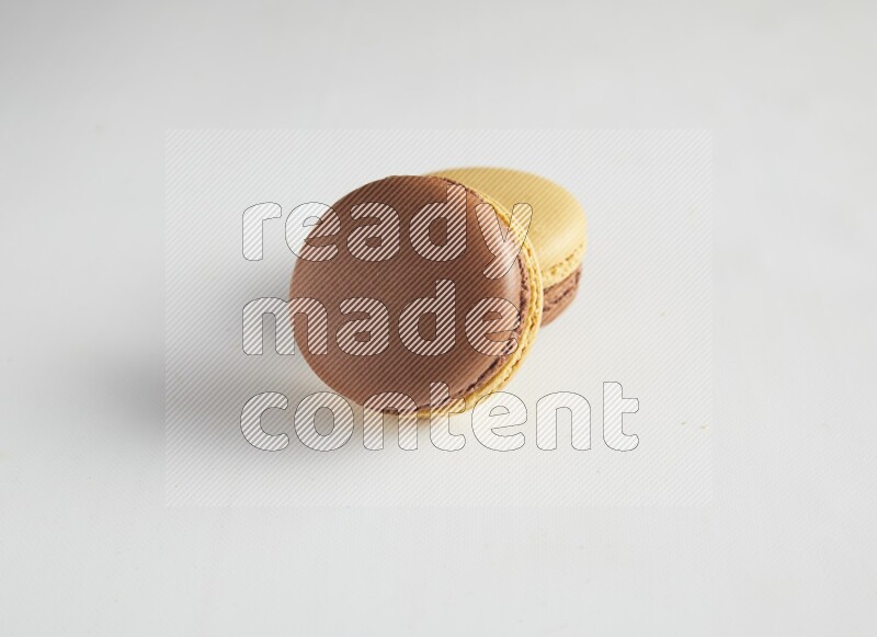 45º Shot of two Yellow and Brown Chai Latte macarons on white background