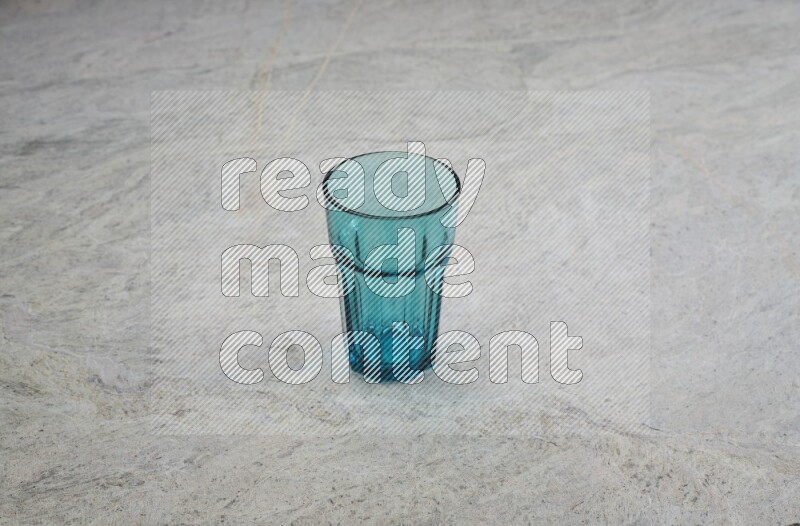 A turquoise glass cup on grey marble background