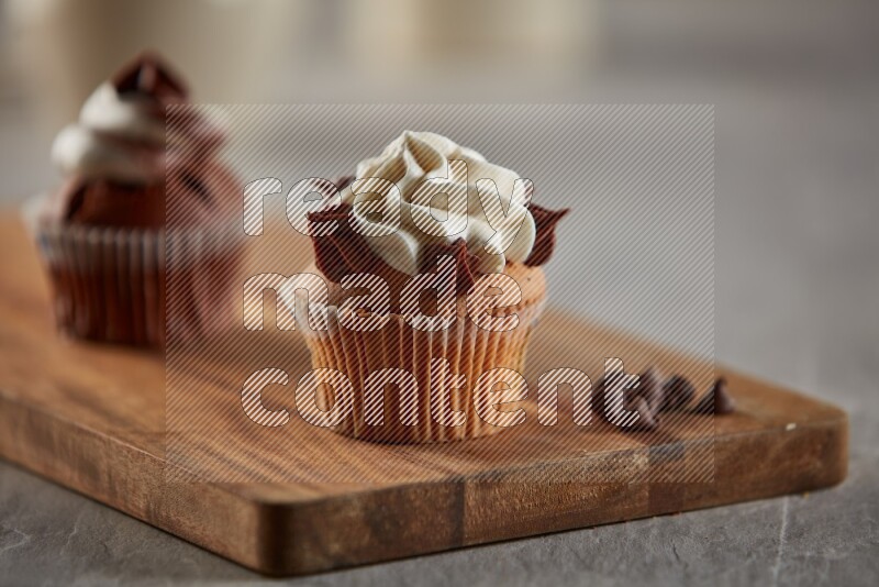 Vanilla cupcake topped with cream on a wooden board