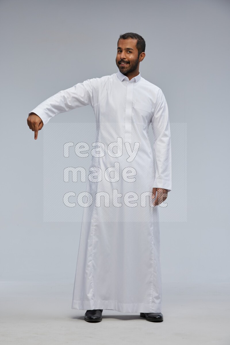Saudi man Wearing Thob standing interacting with the camera on Gray background