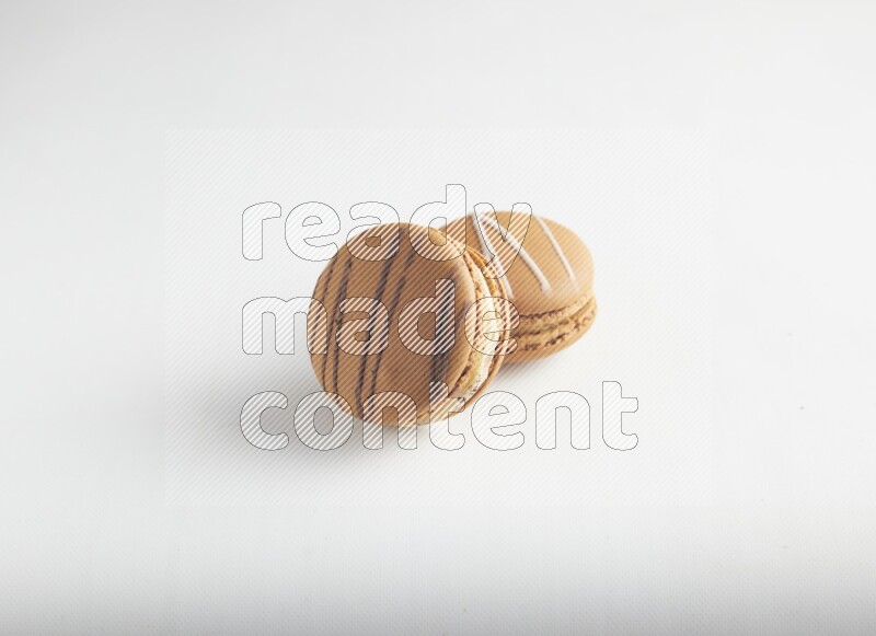 45º Shot of of two assorted Brown Irish Cream, and light brown  Almond Cream macarons on white background