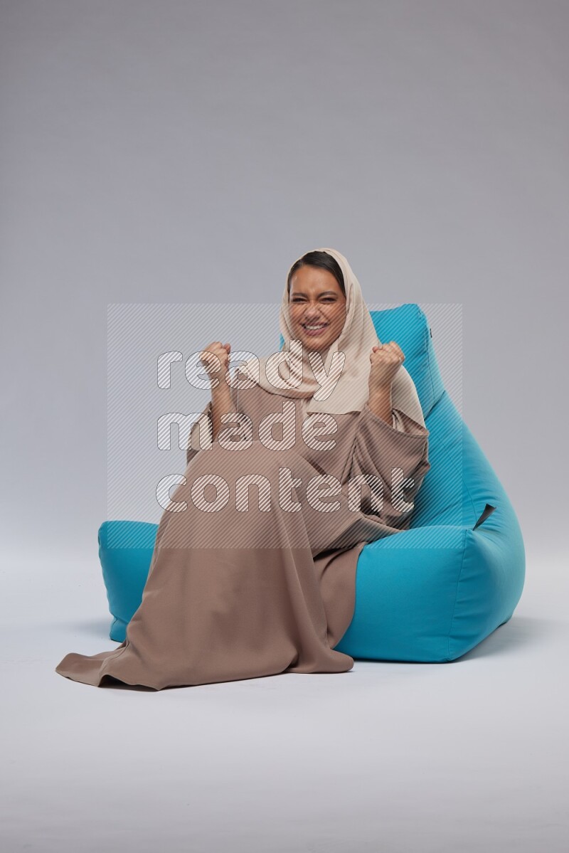 A woman sitting on a blue beanbag and interacting with the camera