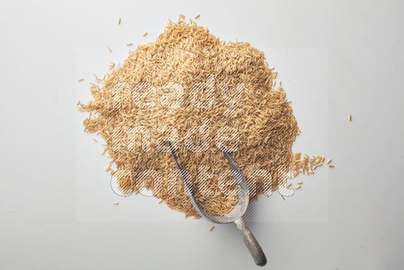 Top-view of a long grain brown rice, and shovel on white background