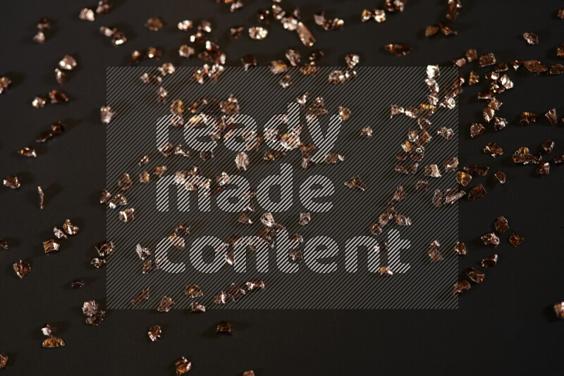 Bronze shimmering fragments of glass scattered on a black background