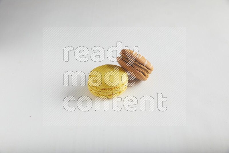 45º Shot of of two assorted Brown Irish Cream, and Yellow Lemon macarons on white background