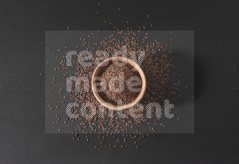 A wooden bowl full of flax surrounded by the seeds on a black flooring in different angles