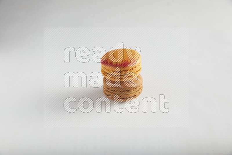 45º Shot of of two assorted Brown Irish Cream, and Orange Exotic macarons on white background