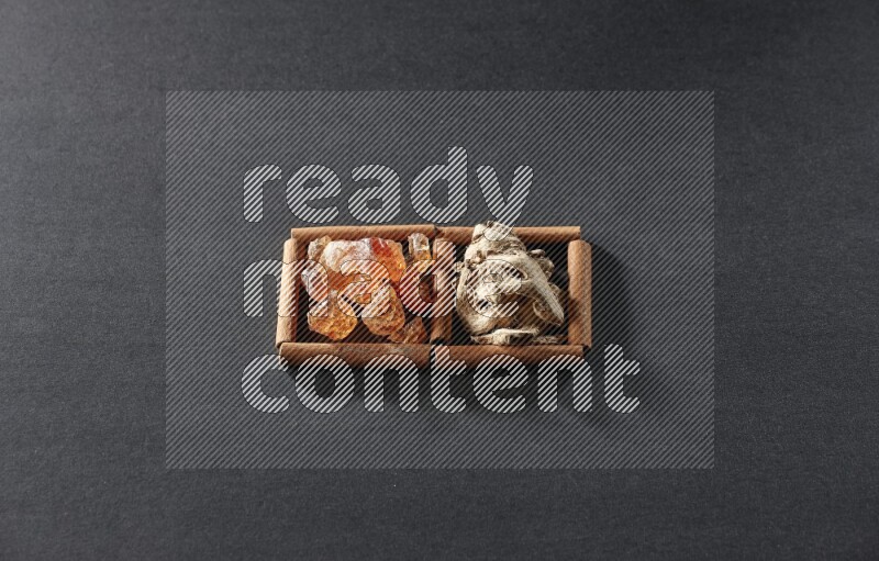 2 squares of cinnamon sticks full of dried ginger and gum arabic on black flooring