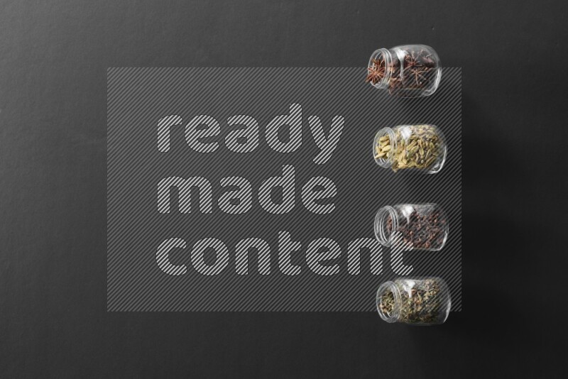 قرنفل وحبوب الهيل وريحان مجفف ويانسون نجمي في أوعية زجاجية علي خلفية سوداء