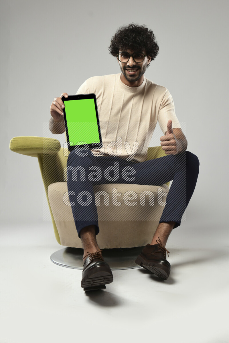 A man wearing casual sitting on a chair showing a tablet screen on white background