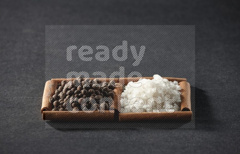 2 squares of cinnamon sticks full of white salt and allspice on black flooring
