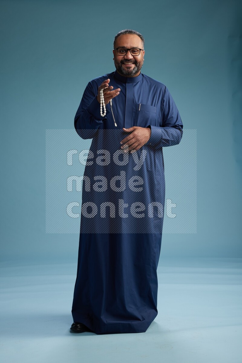 Saudi Man without shimag Standing Interacting with the camera on blue background