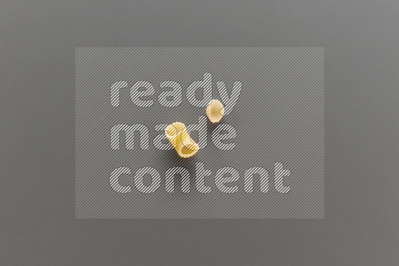 Elbow pasta with other types of pasta on grey background