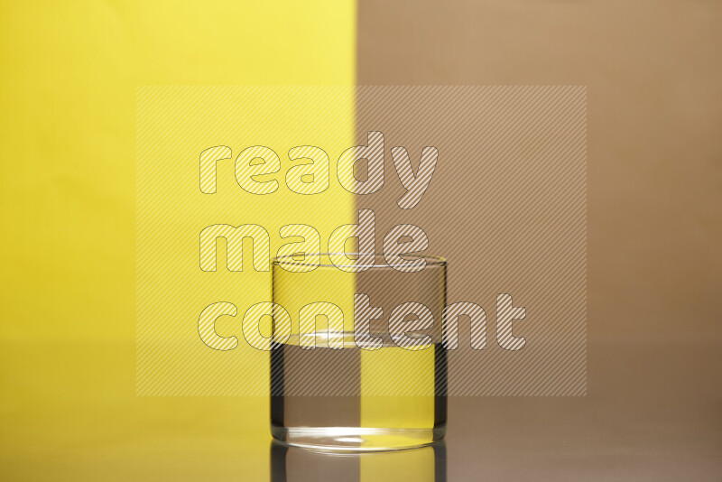The image features a clear glassware filled with water, set against yellow and beige background