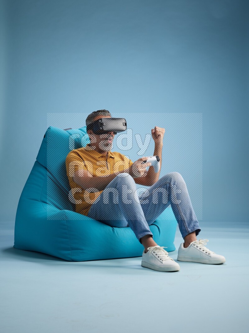A man sitting on a blue beanbag and gaming with VR