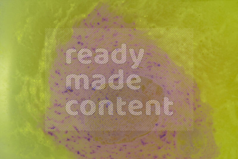 The image captures a dramatic splatter of purple paint over a yellow backdrop