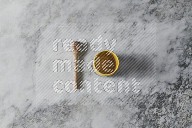 Multicolored pottery cup with wooden honey dipper on the side on grey marble background