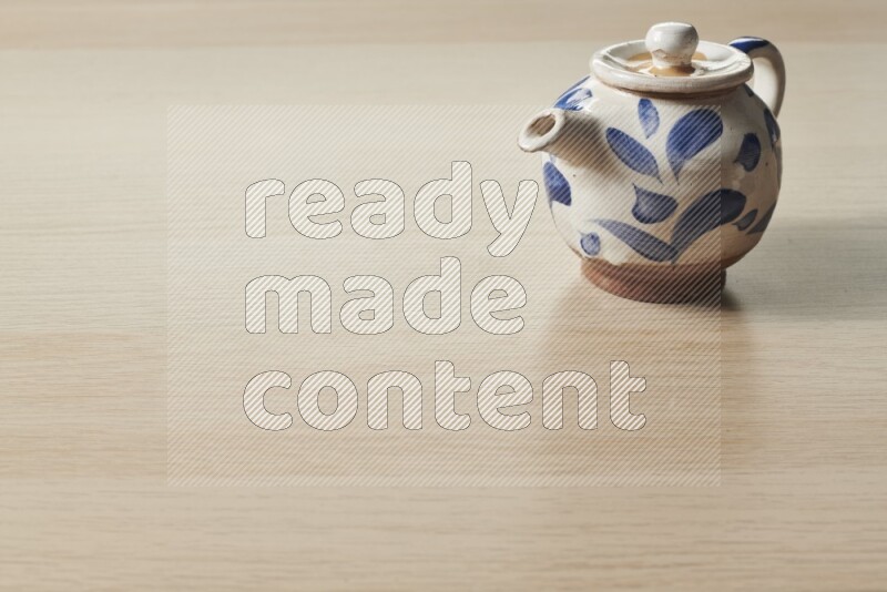 A pottery teapot on light wooden background