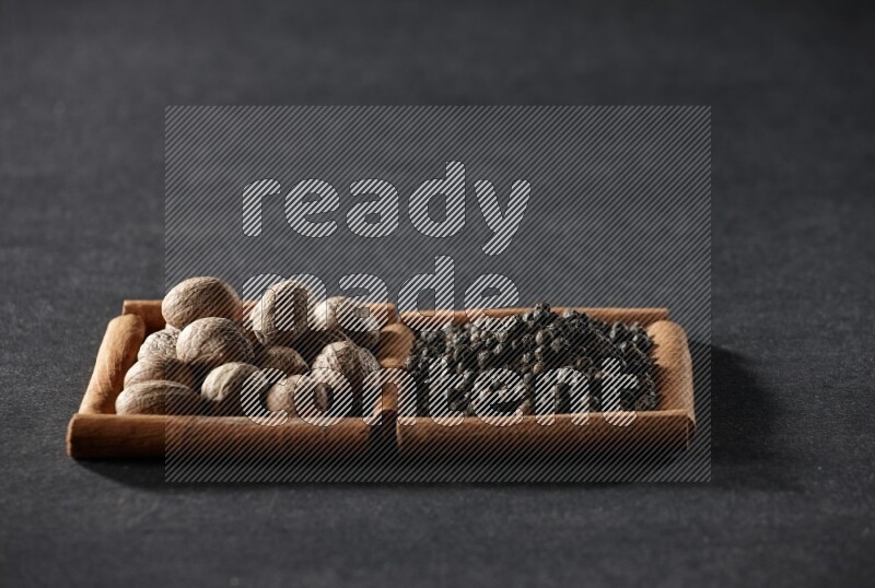 2 squares of cinnamon sticks full of nutmegs and black peppers on black flooring