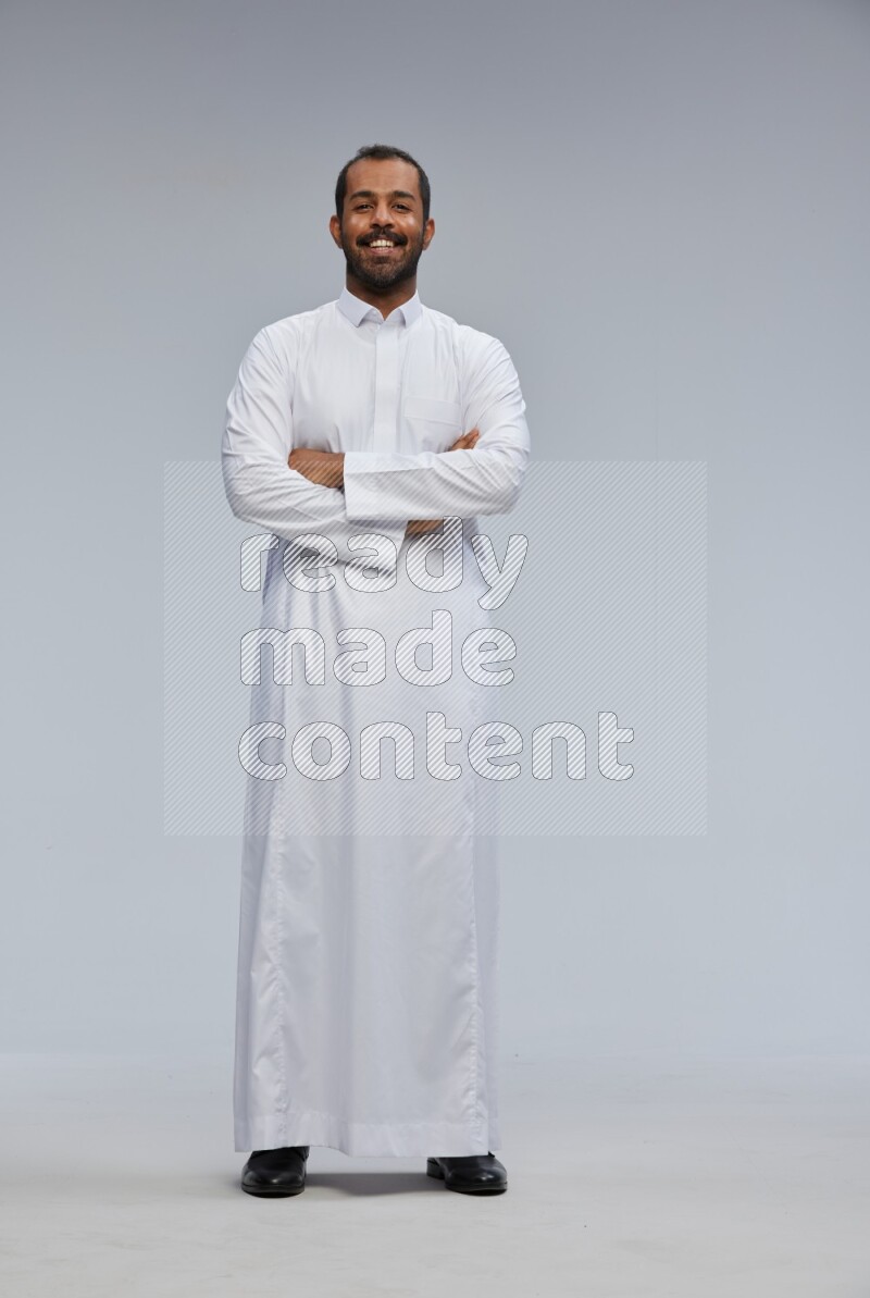 Saudi man wearing Thob standing with crossed arms on Gray background