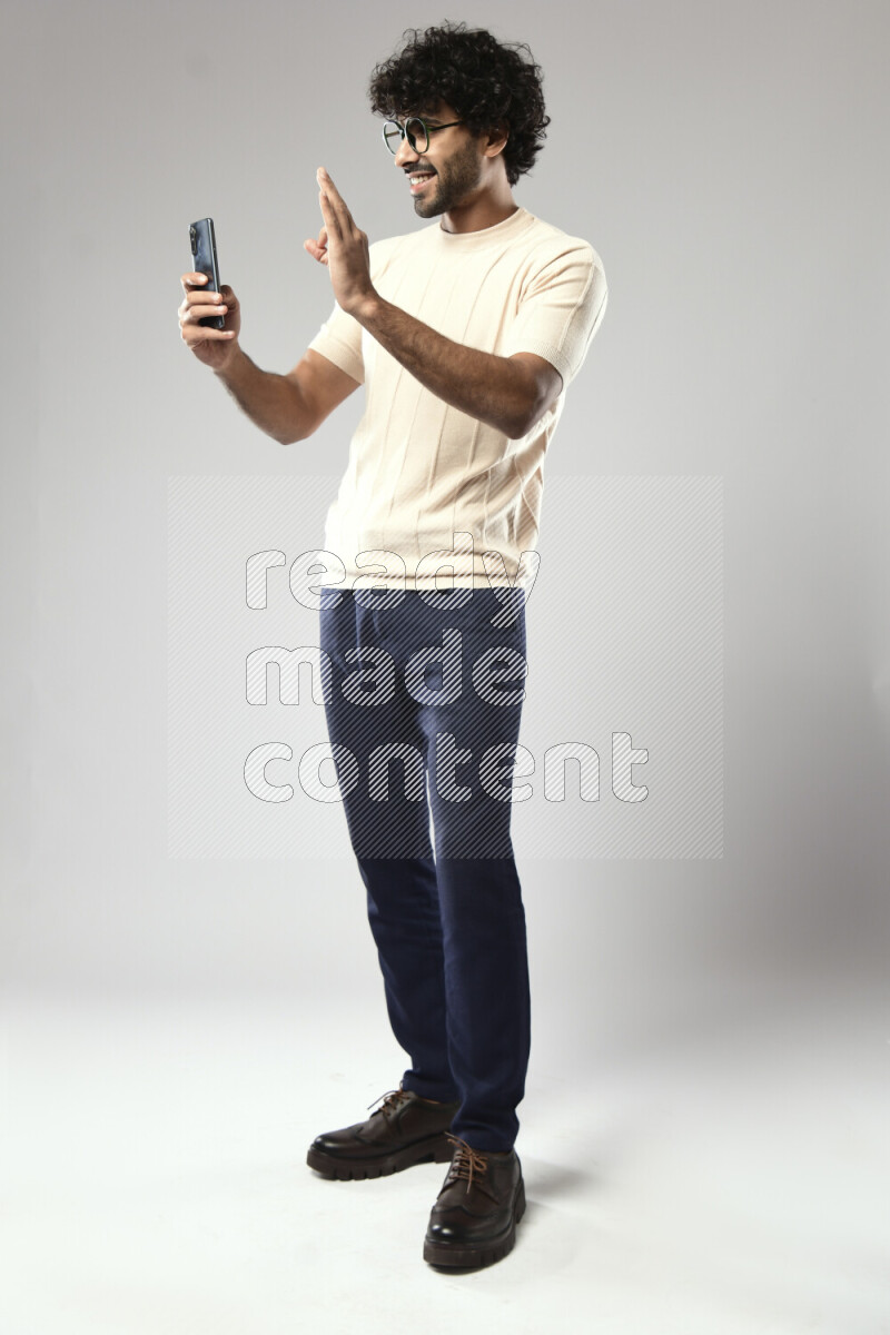A man wearing casual standing and shooting with his phone on white background