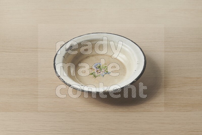 صحن معدني عتيق على خلفية خشبية فاتحة