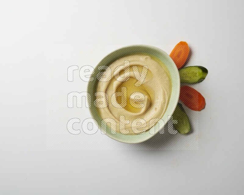 Hummus in a green plate garnished with olive oil on a white background