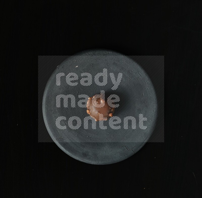 تشكيلة من الحلويات في طبق فخاري أسود على خلفية سوداء