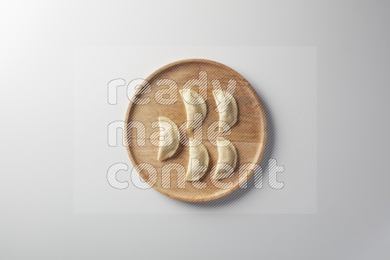 Five Sambosas on a wooden round plate on a white background